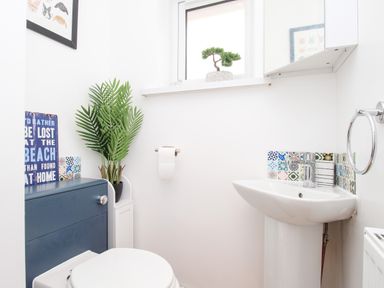 A small bathroom with a toilet sink a plant and a window at The White House in Weymouth