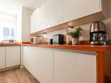 A kitchen with a coffee maker microwave bread box plants and shelves at Chy Fistral in Newquay