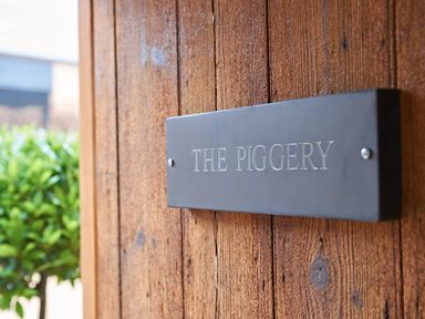 A sign on a wooden door reading The Piggery at The Piggery in Ledbury near Welland