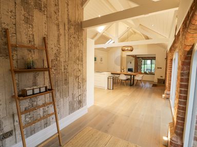 An open plan living space with wooden flooring exposed brick arches shelves and dining table at The Piggery in Ledbury near Welland