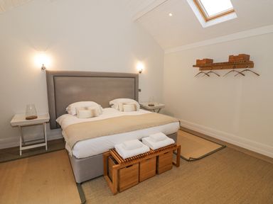 A bedroom with a double bed side tables with glass lamps hangers on the wall at The Piggery in Ledbury near Welland
