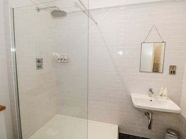 A bathroom with a walk in shower fixed wall mirror and a wall mounted sink at The Piggery Ledbury near Welland
