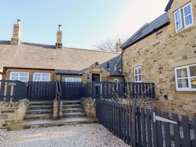 Stone cottages with slate roofs and black wooden fences at Ash Cottage in Lucker near Warenford