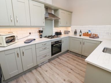 A kitchen with cabinets a gas stove an oven a toaster a knife block and a sink at Ash Cottage in Lucker near Warenford