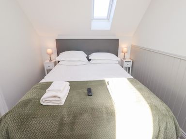 A bedroom with a double bed with pillows blankets bedside tables lamps and towels at Ash Cottage in Lucker near Warenford