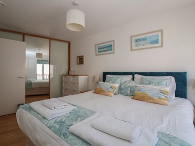 A bedroom with a bed with pillows and towels a dresser with a lamp and a mirrored closet at Skylark in Southwold
