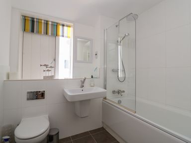 A bathroom with a toilet sink and bathtub with shower at Skylark in Southwold