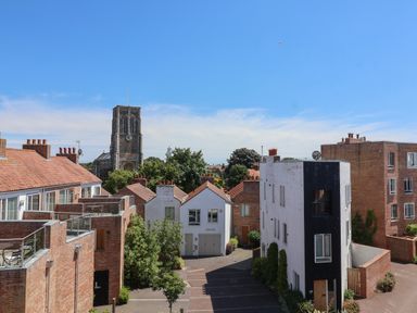 A view of rooftops and a church tower under a clear blue sky at Skylark in Southwold