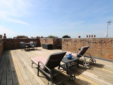 A roof terrace with deck chairs and a dining table at Skylark in Southwold
