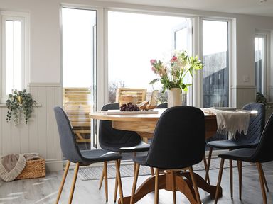 A dining room with a wooden table and six chairs near large glass doors at Elm Cottage in Lucker near Warenford