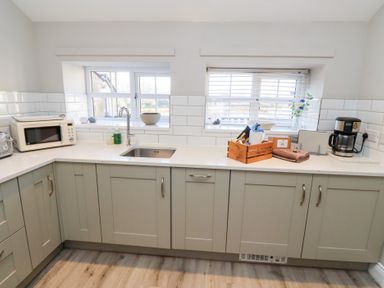A kitchen with sink microwave coffee maker and wooden crate on countertop at Elm Cottage in Lucker near Warenford