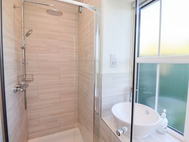 A shower area with glass door a round basin sink and a window in a bathroom at Elm Cottage in Lucker near Warenford