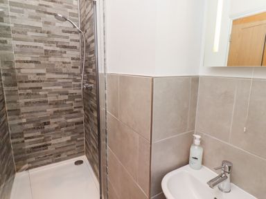 A bathroom with a shower area and a sink with a soap dispenser at Elm Cottage in Lucker near Warenford