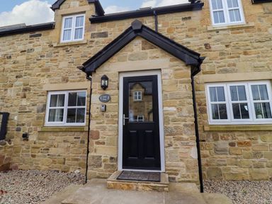 Front entrance with black door and stone walls at Oak Cottage in Lucker near Warenford