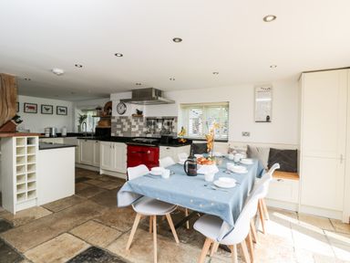 A kitchen and dining area with a table set for breakfast and kitchen cabinets at 2 Dewars Farm Cottages in Middleton Stoney
