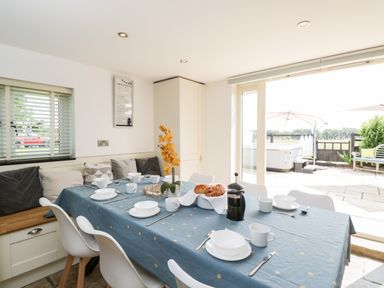 A dining area with a blue tablecloth on a table set with white dishware and cups at 2 Dewars Farm Cottages in Middleton Stoney