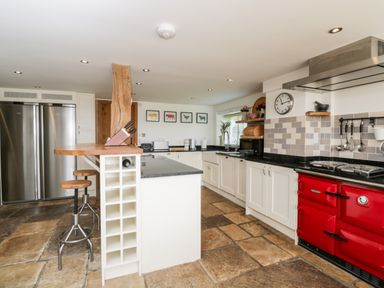 A kitchen with white cabinets a red oven and stainless steel appliances at 2 Dewars Farm Cottages in Middleton Stoney