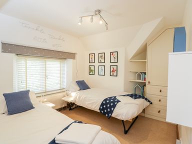 A bedroom with two single beds framed pictures on a wall and a built in cabinet 2 Dewars Farm Cottages Middleton Stoney