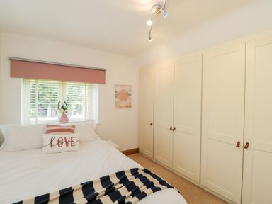 A bedroom with a bed near a window and built in wardrobes at 2 Dewars Farm Cottages in Middleton Stoney