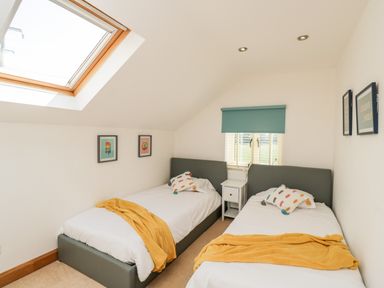 A bedroom with two single beds a skylight and a small window at 2 Dewars Farm Cottages in Middleton Stoney