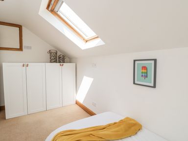 A bedroom with a skylight window white cabinets and a bed with a yellow blanket at 2 Dewars Farm Cottages in Middleton Stoney