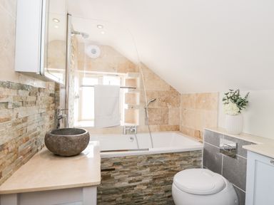 A bathroom with a stone sink a bathtub with a shower and a toilet at 2 Dewars Farm Cottages in Middleton Stoney