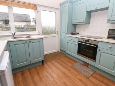 A kitchen with blue cabinets wooden floor and a stainless steel oven at Ramblers Rest in St Just