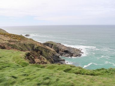 A coastal landscape with rocky cliffs and grassy hills overlooking the ocean at Ramblers Rest in St Just