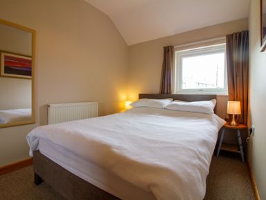 A bedroom with a double bed two bedside lamps a window and a mirror at Ramblers Rest in St Just