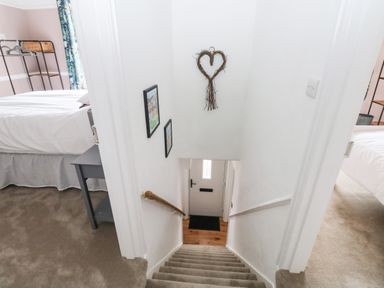 A staircase with handrails leading down to a door with two bedrooms on each side at Rose Cottage in Bishopsteignton