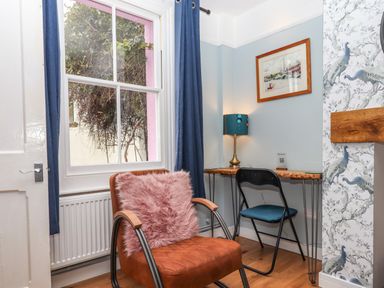 A small seating area with an armchair and desk with chair next to a window at Rose Cottage in Bishopsteignton