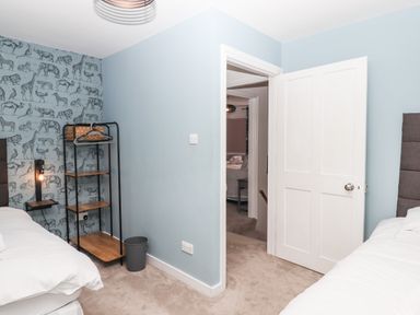 A bedroom with animal wallpaper a metal shelving unit and a white door open to another room at Rose Cottage in Bishopsteignton