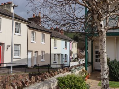 A row of residential houses with a stone wall and leafless tree in the foreground at Rose Cottage in Bishopsteignton