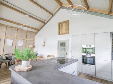 A kitchen and dining area with a large counter island and chairs at Barcud Coch - Red Kite in Garthmyl