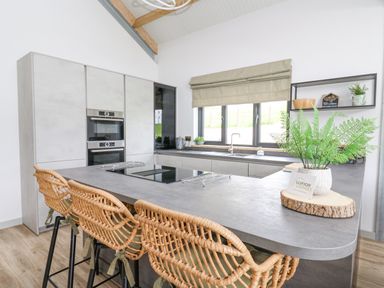 A kitchen with an island counter with bar stools and a plant on the counter at Barcud Coch - Red Kite in Garthmyl