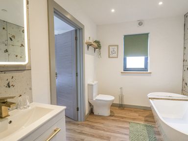 A bathroom with a toilet sink bathtub window and door at Barcud Coch - Red Kite in Garthmyl