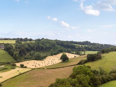 A landscape with hay bales in fields at Barcud Coch - Red Kite Garthmyl