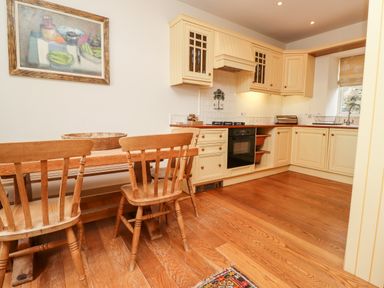 A kitchen with wooden chairs and table and cream cabinets at Harness Lodge in Seahouses
