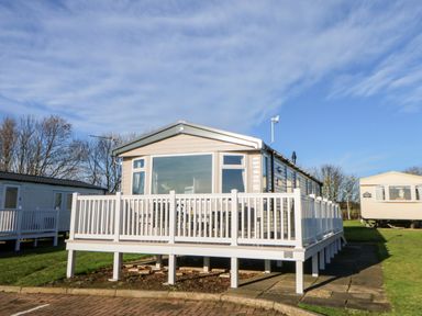 A mobile home with a white railing deck on a grassy plot with other mobile homes nearby at 17 Summer Meadows in Ashington