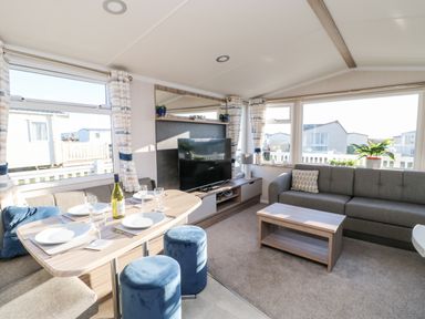 A living room with a dining table set with plates and glasses a television on a stand a sofa and a coffee table at 17 Summer Meadows in Ashington