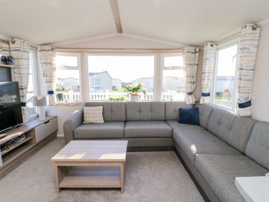 A living room with a grey sectional sofa a wooden coffee table and a tv on a stand at 17 Summer Meadows in Ashington