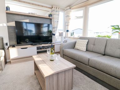 A living room with a grey sofa and coffee table in front of a television at 17 Summer Meadows in Ashington