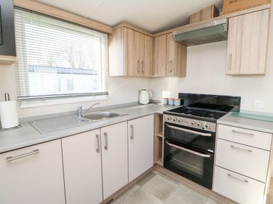 A kitchen with a stainless steel sink stove oven wooden cabinets and a window at 17 Summer Meadows in Ashington