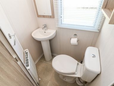 A small bathroom with a toilet sink window with blinds and a radiator at 17 Summer Meadows in Ashington