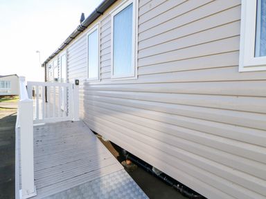 Exterior side view of a mobile home with white windows and a white ramp with railing at 17 Summer Meadows in Ashington