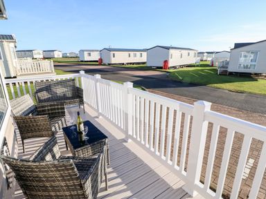 A balcony with wicker furniture and a table with a bottle and glasses at 17 Summer Meadows in Ashington