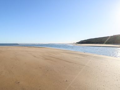 A sandy beach with water and hills under a clear sky at 17 Summer Meadows in Ashington