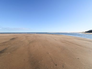 A sandy beach with the ocean and a clear sky at 17 Summer Meadows in Ashington