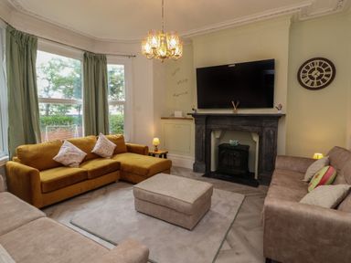 A living room with sofas a fireplace a large television and a window with curtains at The Furness Haven in Barrow-In-Furness