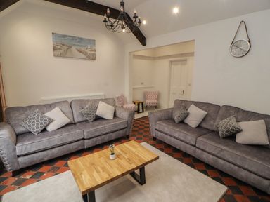 A living room with two gray sofas a wooden coffee table and two pink patterned chairs at The Furness Haven in Barrow-In-Furness